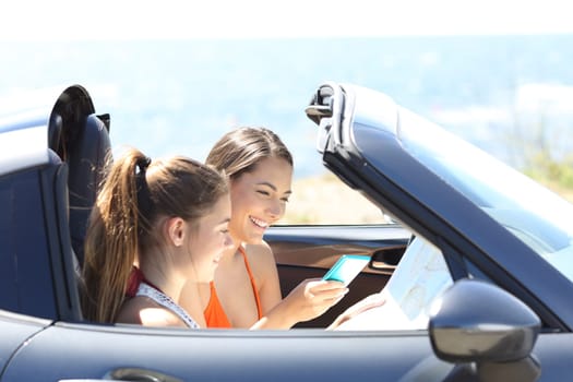 Tourists in a convertible car searching destination online on summer vacation
