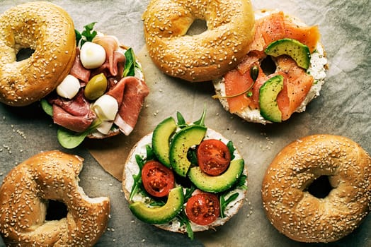 Bagel sandwich with avocado, salmon, prosciutto and mozzareela cheese. Healthy food.