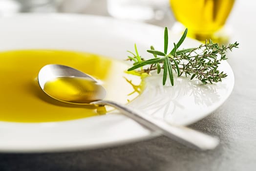 Healthy olive oil with herbs pouring with spoon close up