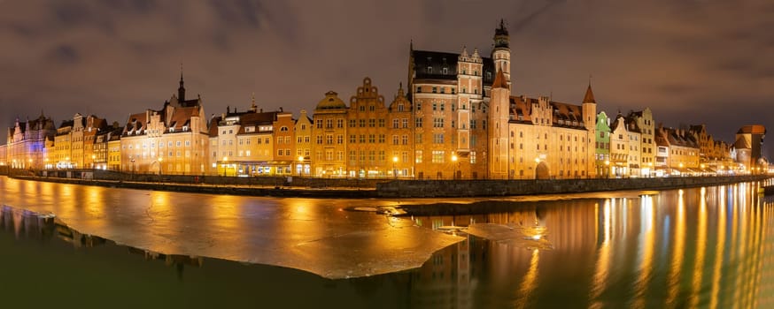 Gdansk evening panorama with medieval gates and Old Town facades on the bank of the Motlawa river.