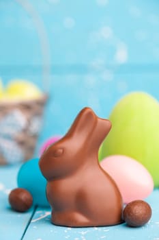Delicious chocolate Easter bunny, eggs and sweets on rustic background