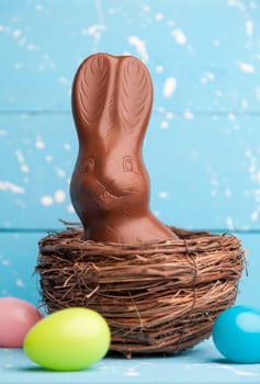 Delicious chocolate Easter bunny, eggs and sweets on rustic background