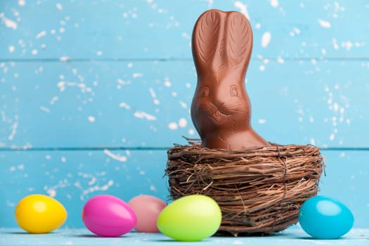 Delicious chocolate Easter bunny, eggs and sweets on rustic background