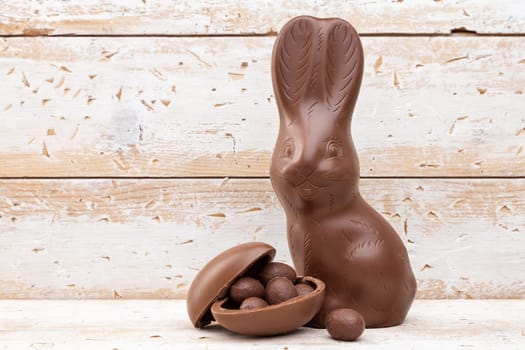 Delicious chocolate Easter bunny, eggs and sweets on rustic background