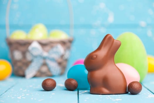 Delicious chocolate Easter bunny, eggs and sweets on rustic background