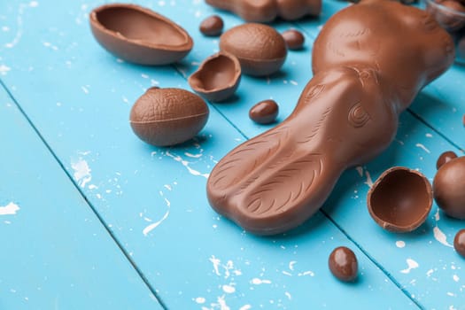 Delicious chocolate Easter bunny, eggs and sweets on rustic background