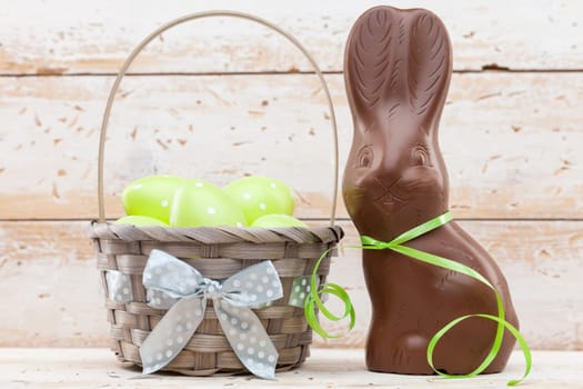 Delicious chocolate Easter bunny, eggs and sweets on rustic background
