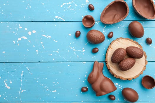 Delicious chocolate Easter bunny, eggs and sweets on rustic background