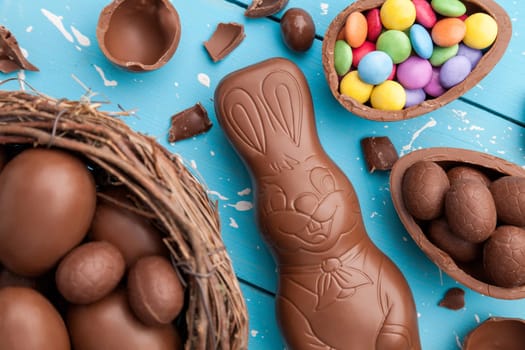 Delicious chocolate Easter bunny, eggs and sweets on rustic background