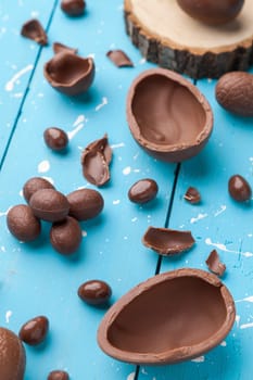 Delicious chocolate Easter bunny, eggs and sweets on rustic background
