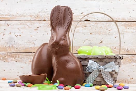 Delicious chocolate Easter bunny, eggs and sweets on rustic background