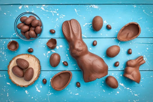 Delicious chocolate Easter bunny, eggs and sweets on rustic background