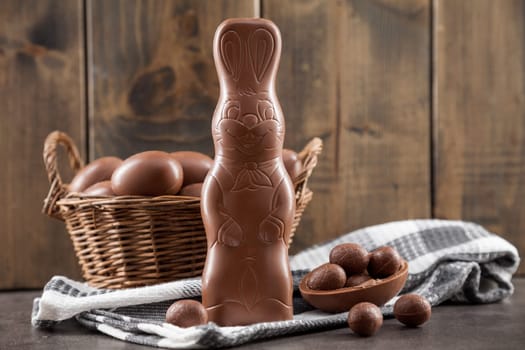 Delicious chocolate Easter bunny, eggs and sweets on rustic background