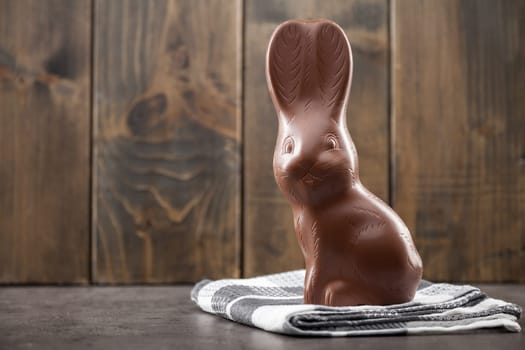 Delicious chocolate Easter bunny, eggs and sweets on rustic background
