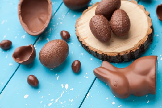 Delicious chocolate Easter bunny, eggs and sweets on rustic background