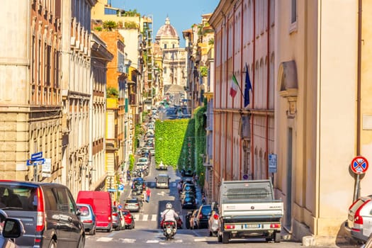 Rome Italy - August 26, 2018: Italian Street with cars and tourists with a basilica on the hill