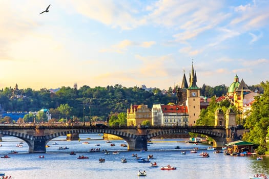The Vltava River in Prague with people floating on paddleboats near Manes Bridge.