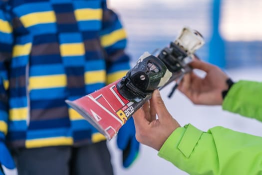 Szklarska Poreba, Poland - February 2019 : Ski instructor holding little boy skis and explaining him the safety features of equipment