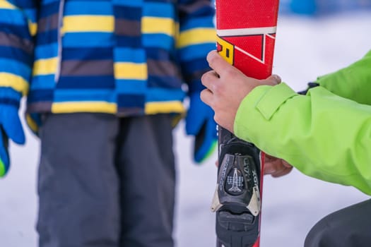 Szklarska Poreba, Poland - February 2019 : Ski instructor holding little boy skis and explaining him the safety features of equipment