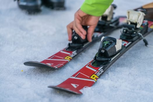 Szklarska Poreba, Poland - February 2019 : Ski instructor explaining the features of skis to his little student and adjusting the locking mechanism