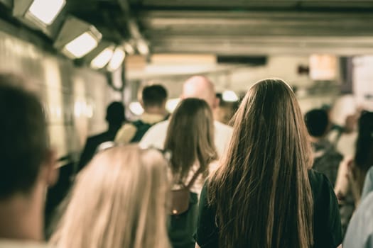 London, England - July 2018 : Crowd of commuters walking inside the underground tube station in a passage between two changing stations