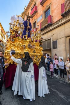 SEVILLE, SPAIN - MARCH 26:  Hooded figures hold up a float carrying Jesus Christ during Holy Week in Seville, Spain on March 26, 2018