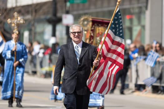 Chicago, Illinois, USA - April 29, 2018  Greek man  carrying the USA flag during the Greek Independence  Day Parade