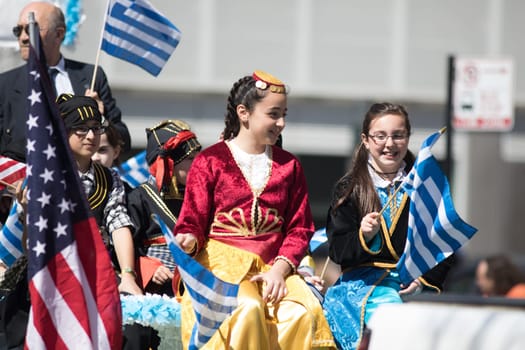 Chicago, Illinois, USA - April 29, 2018 Greek Children wearing traditional clothing waving the greek and usa flag during the Greek Independence  Day Parade