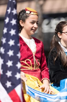 Chicago, Illinois, USA - April 29, 2018 Greek Children wearing traditional clothing waving the greek and usa flag during the Greek Independence  Day Parade