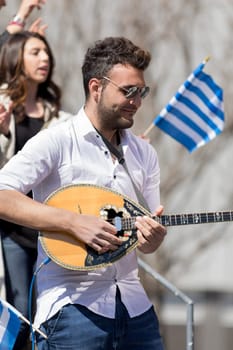 Chicago, Illinois, USA - April 29, 2018 Greek man playing Baglamas during the  Greek Independence  Day Parade