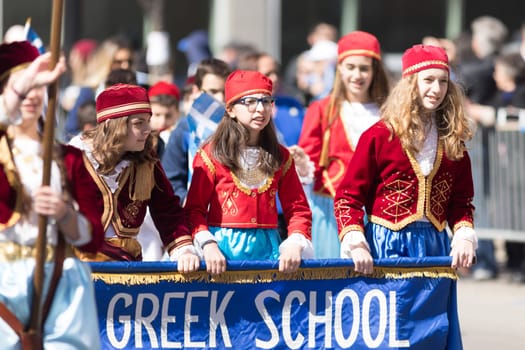 Chicago, Illinois, USA - April 29, 2018 Members of a greek school wearing traditional clothing and waving greek flags during the Greek Independence  Day Parade