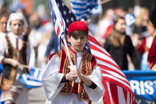 Chicago, Illinois, USA - April 29, 2018  Greek Children wearing traditional clothing and carrying the USA flag during the Greek Independence  Day Parade