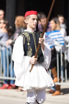 Chicago, Illinois, USA - April 29, 2018 Greek child wearing traditional clothing carrying a flag at the Greek Independence  Day Parade