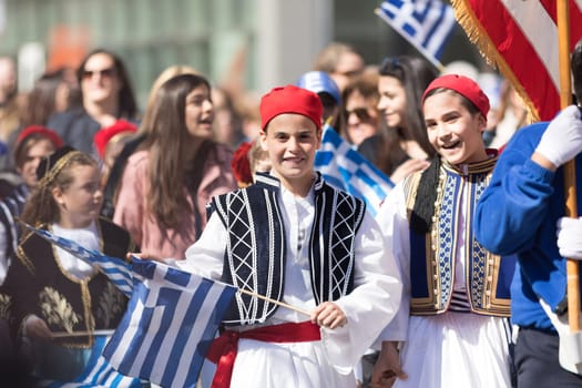 Chicago, Illinois, USA - April 29, 2018 Children wearing traditional clothing waving greek flags during the Greek Independence  Day Parade