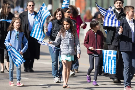 Chicago, Illinois, USA - April 29, 2018 Greek children and adults waving greek flags at the Greek Independence  Day Parade