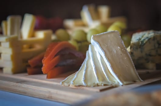 Cheese platter with different cheeses including brie, cheddar and blue cheese, served with grapes