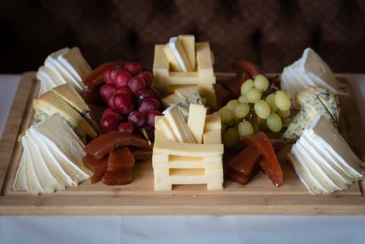 Cheese platter with different cheeses including brie, cheddar and blue cheese, served with grapes