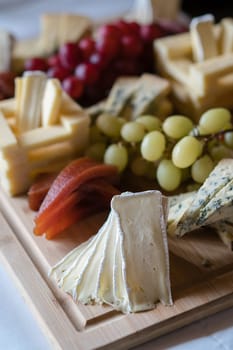 Cheese platter with different cheeses including brie, cheddar and blue cheese, served with grapes