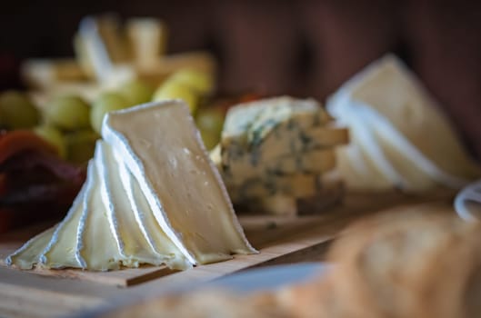 Cheese platter with different cheeses including brie, cheddar and blue cheese, served with grapes