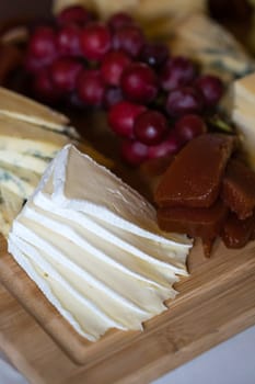 Cheese platter with different cheeses including brie, cheddar and blue cheese, served with grapes