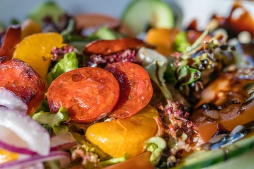 Close-up of a fresh spicy Spanish chorizo summer salad in a white plate