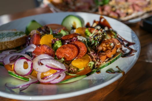 Close-up of a fresh spicy Spanish chorizo summer salad in a white plate