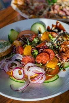 Close-up of a fresh spicy Spanish chorizo summer salad in a white plate