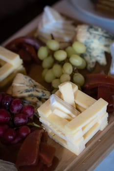 Cheese platter with different cheeses including brie, cheddar and blue cheese, served with grapes