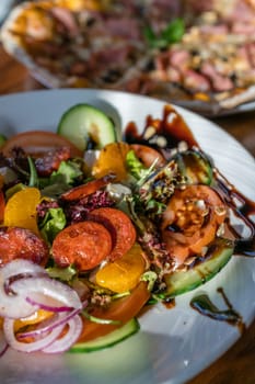Close-up of a fresh spicy Spanish chorizo summer salad in a white plate