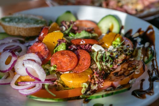Close-up of a fresh spicy Spanish chorizo summer salad in a white plate