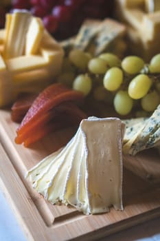Cheese platter with different cheeses including brie, cheddar and blue cheese, served with grapes