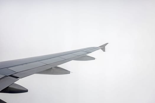 Window view of the wing of an airplane flying into the dense rainy clouds