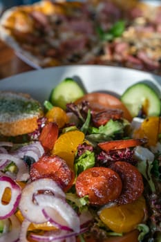 Close-up of a fresh spicy Spanish chorizo summer salad in a white plate