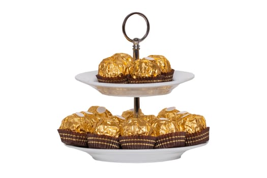 Sweets isolated. Closeup of sweets wrapped in gold paper on an etagerie isolated on white background. Decorations background. Macro.